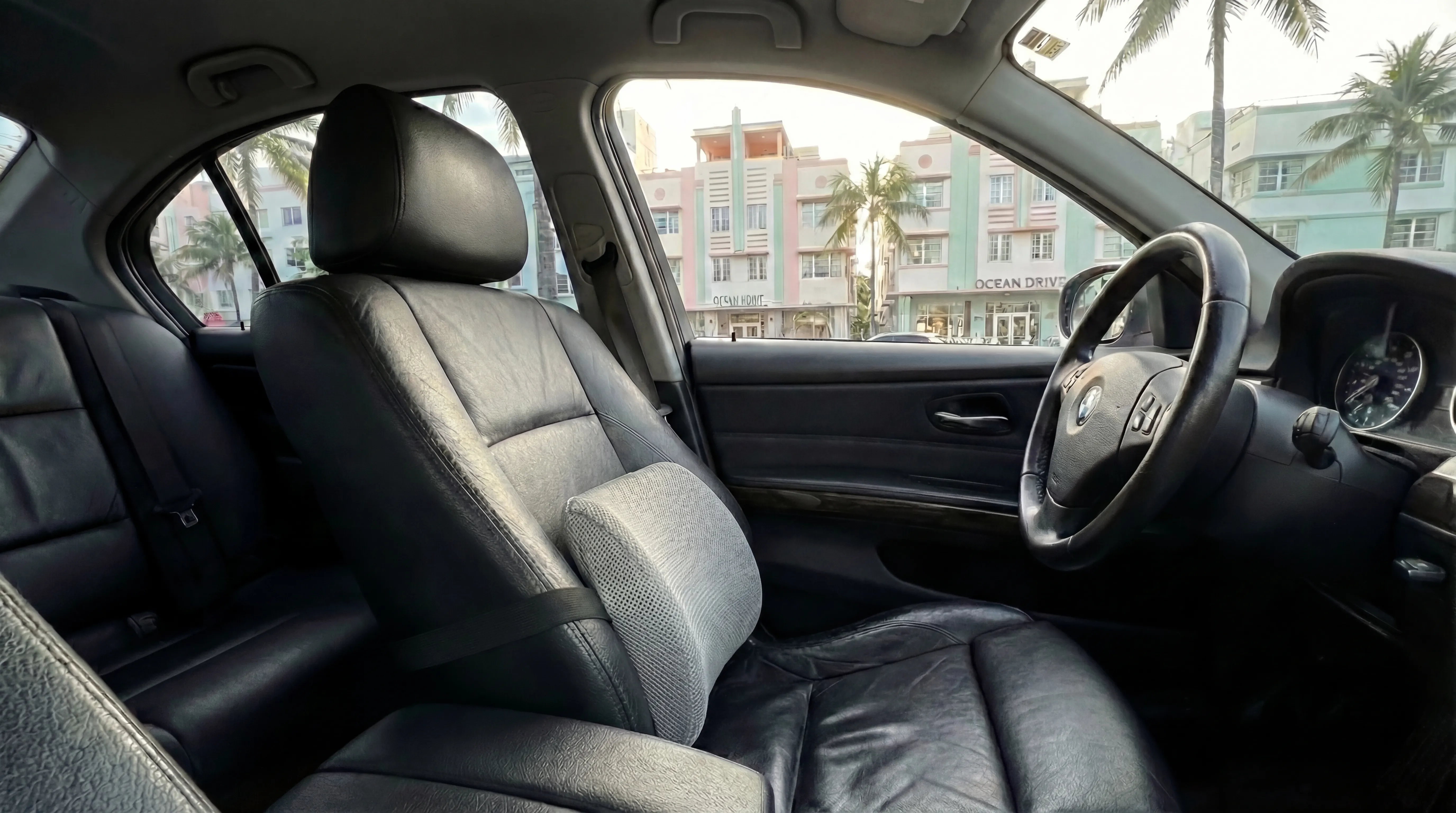 Lumbar support on car seat for driving with sciatica, South Beach Miami's Art Deco neighborhood visible through windshield
